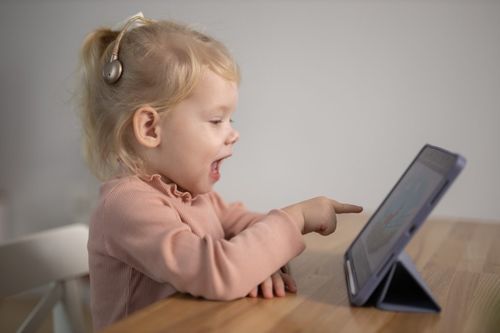 Deaf child girl with cochlear implant studying to hear sounds - recovery after cochlear Implant surgery and rehabilitation concept